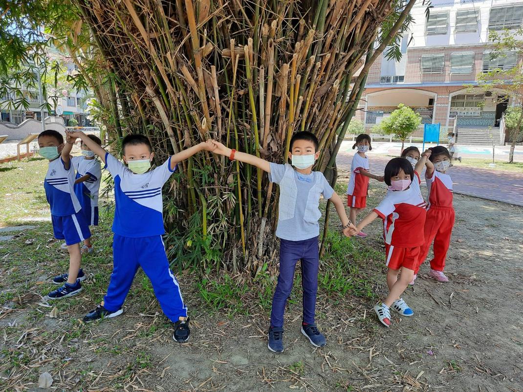 Kinder in roten und blauen Schuluniformen halten sich an den Händen.
