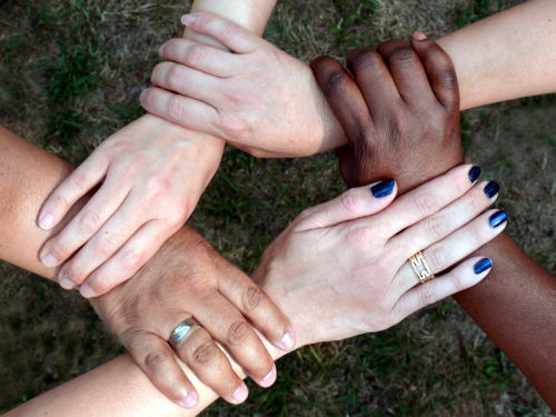 Hände unterschiedlicher Hautfarben bilden gemeinsam einen Kreis.