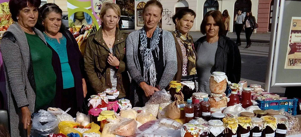 Frauen hinter ihrem Verkaufsstand für Käse, Fruchtsäfte, Honig, eingemachte Früchte und getrocknete Kräuter. 