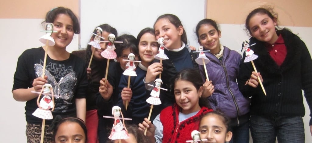 Flüchtlingsmädchen aus Syrien präsentieren lächelnd selbstgebastelte Figuren