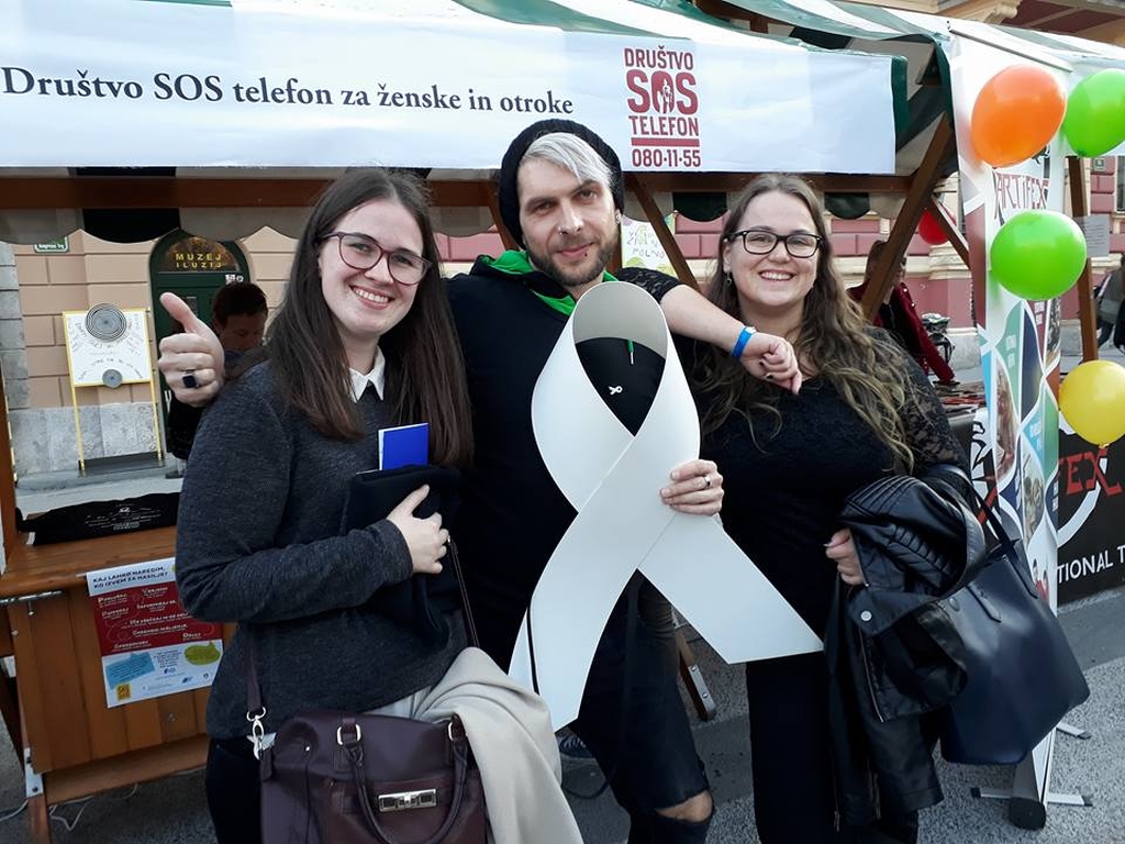 Das Foto zeigt zwei Frauen und einen Mann draussen vor einem Info-Stand. Die Frauen sind Mitarbeiterinnen von SOS Hotline, einer Partnerorganisation des Weltgebetstags in Slowenien. Das Foto stammt von SOS Hotline